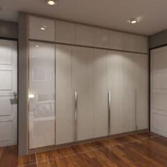 A modern bedroom closet features sleek wooden doors with silver handles. The space is well-lit with recessed lighting, and polished wooden floors add warmth. Two closed doors separate the closet area from the rest of the room. A glimpse of the bed is visible in the reflection.